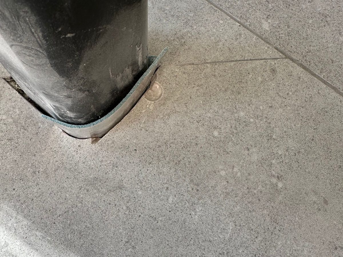 Voor: beschadigde vloertegel rond een paal